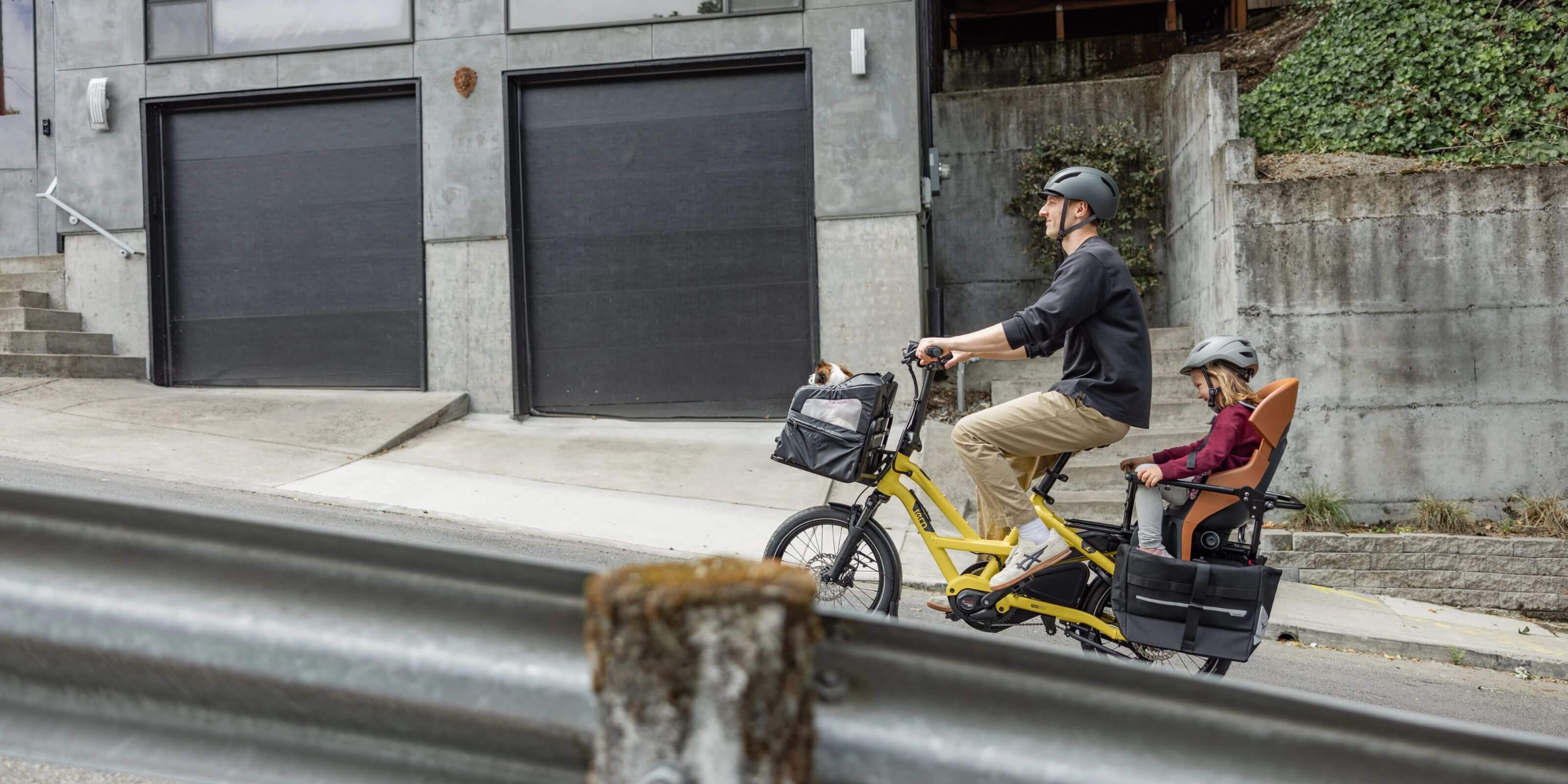 Man riding a Tern HSD P5i electric cargo bike with his child up a steep hill, powered by the Bosch Performance motor.