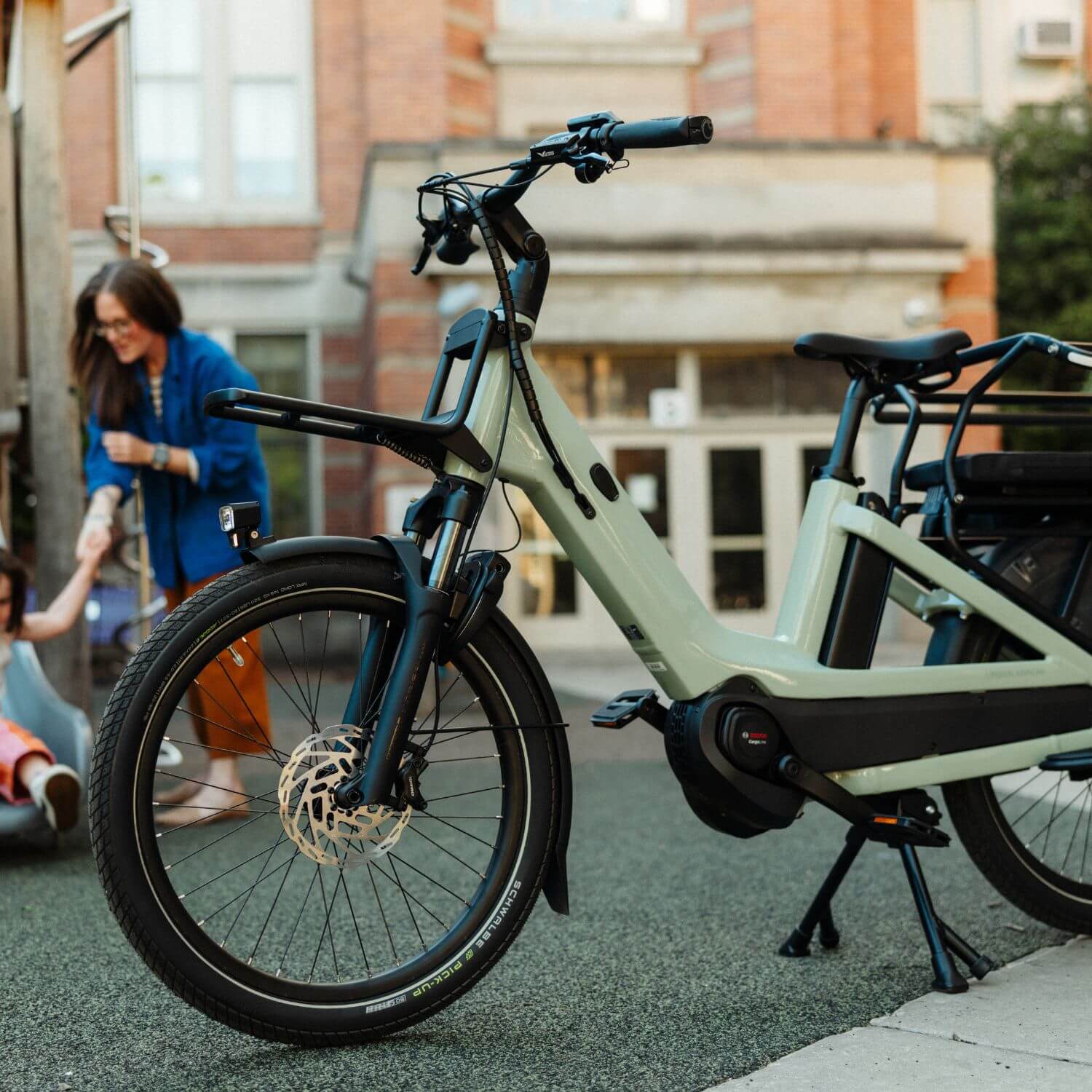 Front three-quarter view of the Urban Arrow Breeze electric cargo bike showing the suspension fork and integrated front rack